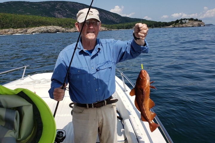 a man holding a fish on a boat in the water
